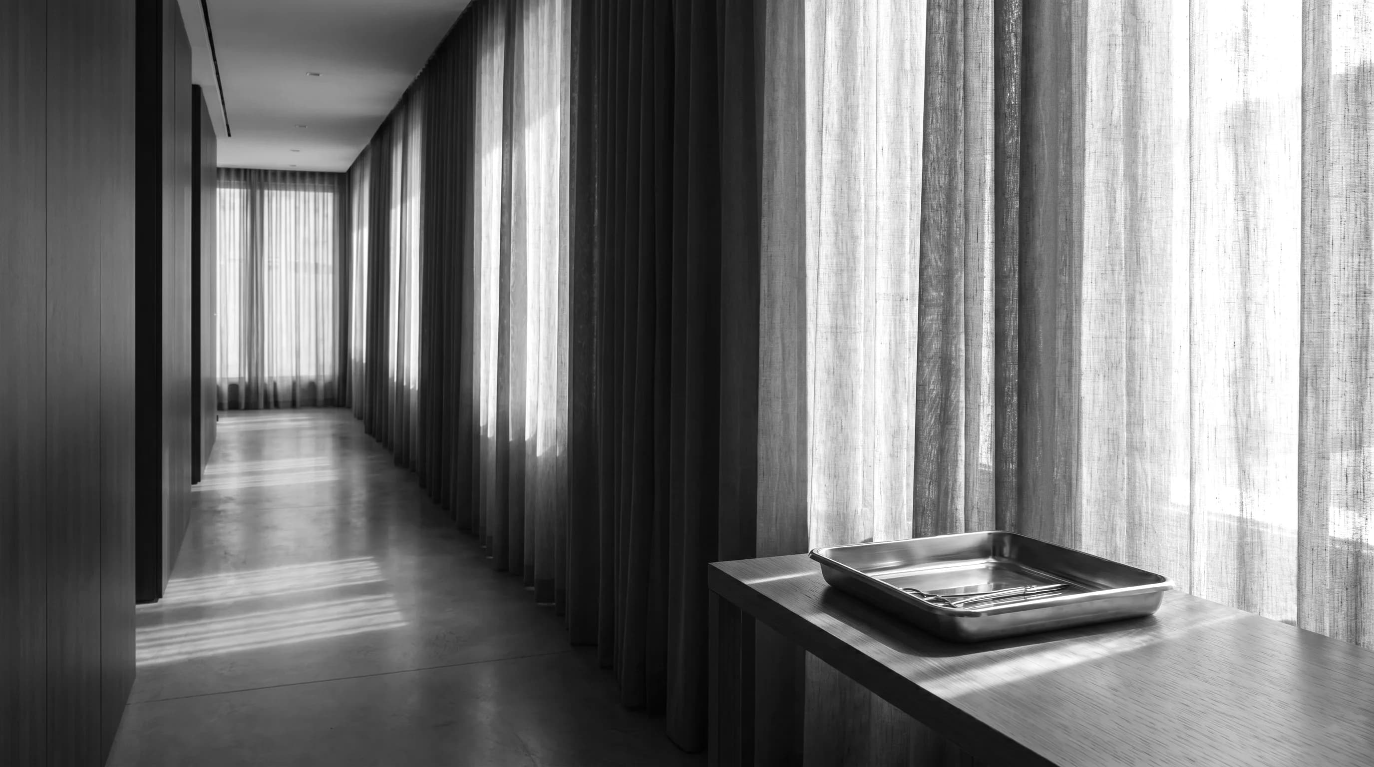 A calm private clinic corridor in soft linen light, representing premier private care groups