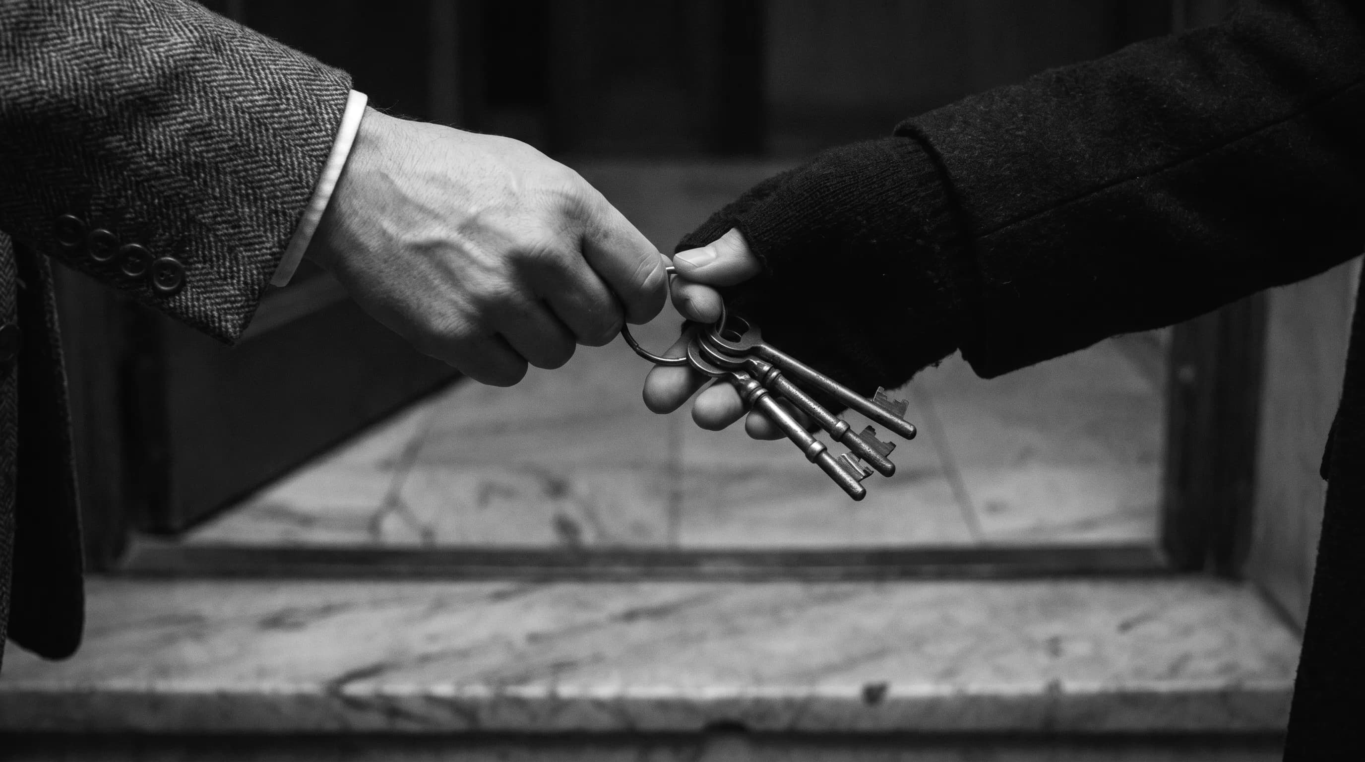 A ring of worn brass keys passing between hands, evoking business succession